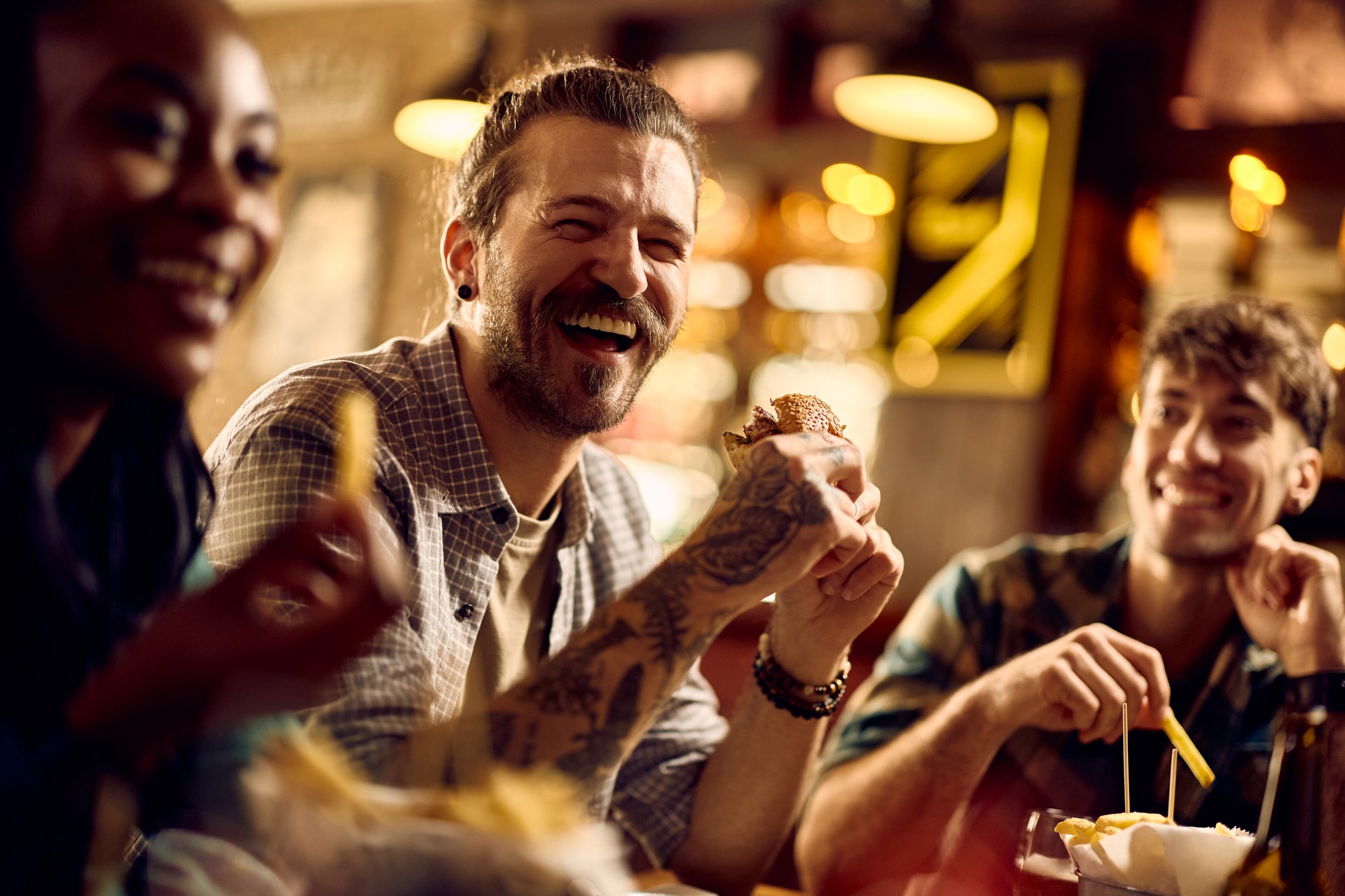 Young man having fun while eating with his friends in a pub.